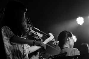 mujer tocando violin con luz de fondo